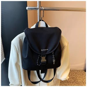 Dettaglio dello zaino in nylon nero con fibbia in metallo e accenti di corda intrecciata