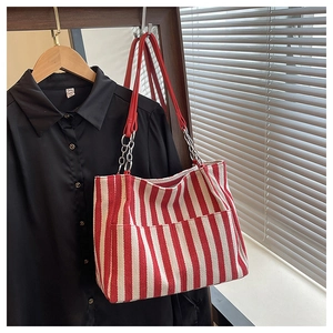 Détail du sac cabas en toile rayée avec bandoulières en cuir rouge et chaîne en métal