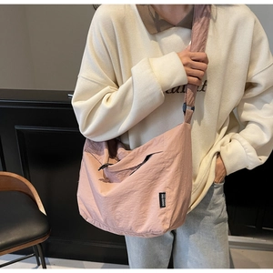Dettaglio della borsa a tracolla in nylon rosa con trama stropicciata ed etichetta