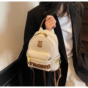Détails du sac à dos en cuir blanc avec écusson d'ours en peluche et clous dorés