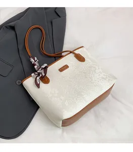 Detail of faux snakeskin tote bag with brown leather handles and a printed silk scarf