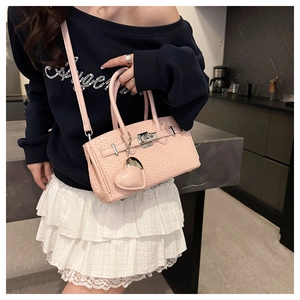 Detailed view of pink woven texture handbag with metallic lock and heart charm