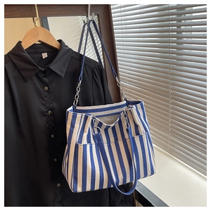 Détail du sac cabas en toile avec rayures bleues et bandoulière en chaîne argentée