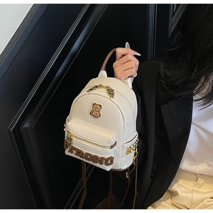 Détail du sac à dos en PU crème avec écusson d'ours, lettres en peluche et clous dorés