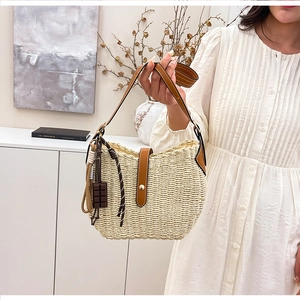 Detail of hand-woven straw bucket bag with brown leather trim and cute chocolate charm