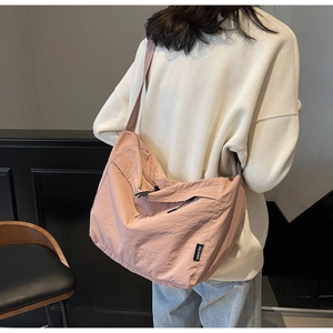 Vista posteriore del modello con una grande borsa a tracolla rosa polvere e spallina