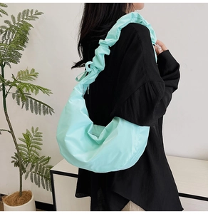 Detail of mint green crescent bag with ruched shoulder strap on model side view