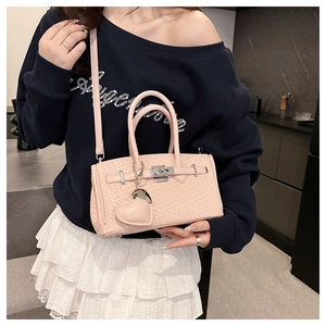 Detail of light pink woven leather mini bag featuring metal turn-lock and heart charm