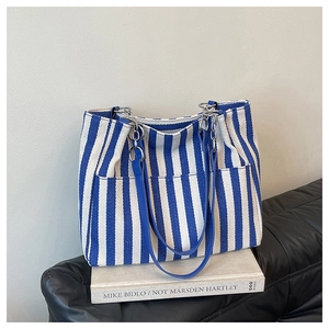 Détail du cabas en toile à rayures bleues et blanches, lanières cuir et chaîne métal
