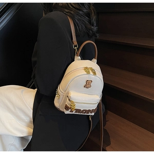 Détail du sac à dos en PU crème avec broderie ours et décorations en peluche