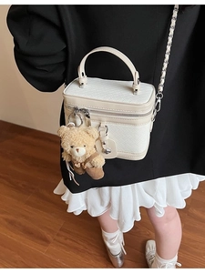 Sac bandoulière en cuir tressé blanc avec breloque ours et bandoulière chaîne sur le mannequin