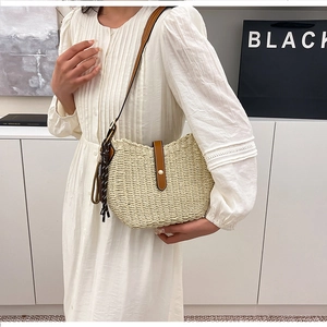 Detail of woven straw shoulder bag with leather strap and magnetic buckle closure