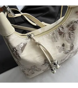 Detail of cream sequin butterfly bag showing the smooth zipper and silver bead charms