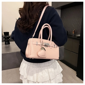 Close-up of pink crocodile texture Kelly bag with silver lock and heart charm