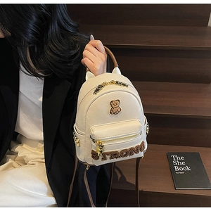 Détail du mini sac à dos en similicuir crème avec écussons d'oursons et breloque en métal