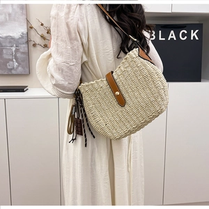 Detail of woven straw bucket bag with brown leather trim and chocolate charm