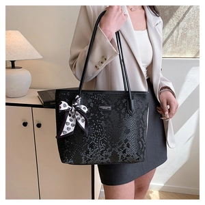 Detail of black snake pattern tote bag with polka dot scarf and silver brand plaque