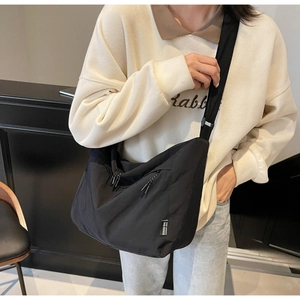 Dettaglio della borsa a tracolla in nylon nero con etichetta tessuta e tracolla larga