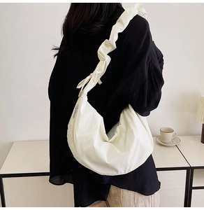 Close-up of a cream pleated crescent bag with a wide ruched shoulder strap for women
