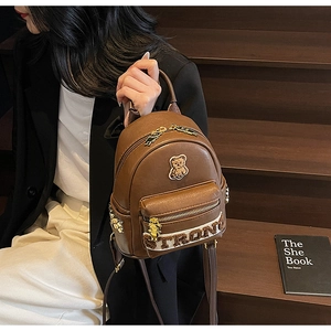 Détail d'un mini sac à dos en cuir PU marron avec patch ours 3D et lettrage STRONG