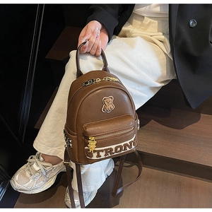 Détail d'un mini sac à dos en similicuir marron avec broderie d'ours et fermeture éclair dorée