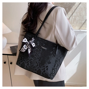 Detail of black snakeskin tote bag with fashion logo and heart print silk scarf accessory