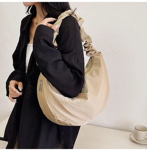 Fashionable beige pleated dumpling bag with silky texture and cloud strap on a model