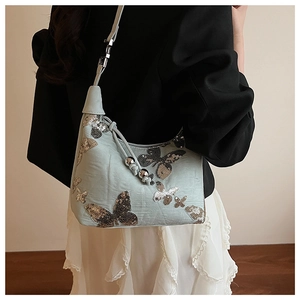 Detail of light blue sequin butterfly pattern on chic shoulder bag with silver hardware