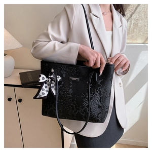 Close-up of black snakeskin embossed tote bag with heart scarf on a stylish model