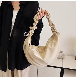 Close-up of beige ruched handle and smooth nylon fabric on a stylish crescent bag