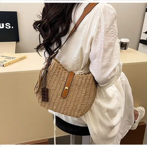 Detail of beige woven straw bucket bag with brown leather strap and chocolate charm