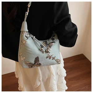 Detail of mint green handbag with butterfly sequins and adjustable strap shown on model