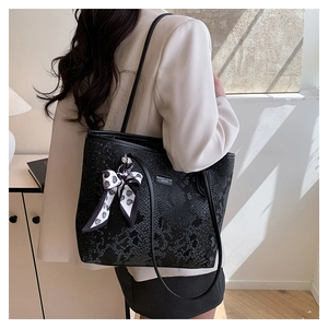 Close-up of black snake pattern tote bag with heart silk scarf and brand tag detail