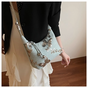 Detail of light blue crossbody bag featuring gold sequin butterflies and drawstring cord