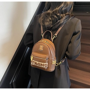 Détail d'un mini sac à dos marron foncé avec broderie ours et clous dorés pyramidaux