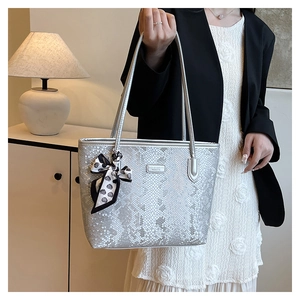 Close-up of silver snakeskin tote bag with black and white polka dot bow charm