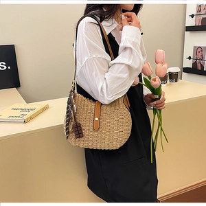 Detail of woven straw shoulder bag with brown leather clasp and cute chocolate charm