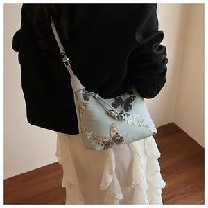 Detail of mint green crossbody bag with sequin butterfly patterns and drawstring closure