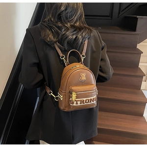 Détail du mini sac à dos en cuir marron avec charm ours et sangle brodée Strong