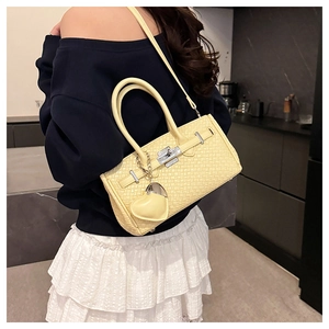 Crossbody view of a yellow woven Kelly bag with silver lock and heart charm