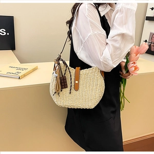 Detail of woven straw bucket bag with brown leather straps and chocolate charm