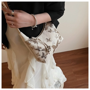 Detailed close-up of butterfly sequin embroidery and metal bead drawstring on beige bag