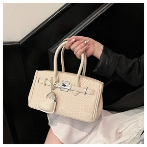 Macro shot of cream-colored woven texture and metal clasp on minimalist Kelly style handbag