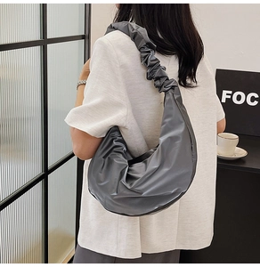 Detailed side view of dark grey nylon moon bag with gathered pleated shoulder strap detail