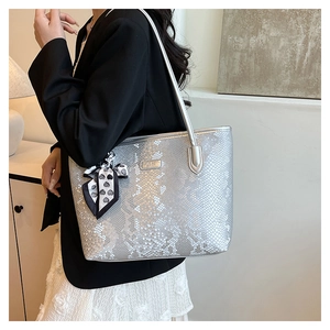 Detail of silver snake-embossed tote bag featuring decorative black and white silk scarf