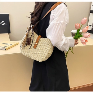 Detail of hand-woven straw bucket bag with brown leather strap and chocolate charm