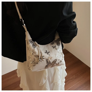 Detail of cream sequin butterfly embroidery on stylish crossbody bag with metal ball accents