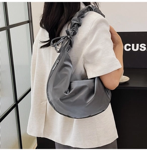 Detail of ruffled shoulder strap and smooth charcoal grey nylon fabric on shoulder bag