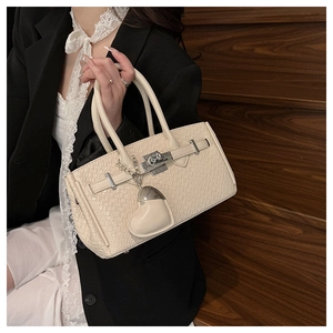 Close-up of woven leather texture and silver turn-lock on a cream Kelly style handbag