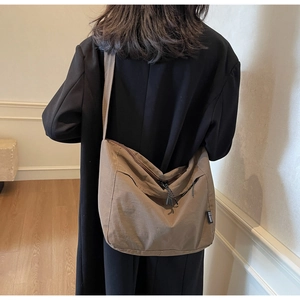 Dettaglio della borsa a tracolla in nylon marrone caffè su modella in interno minimal